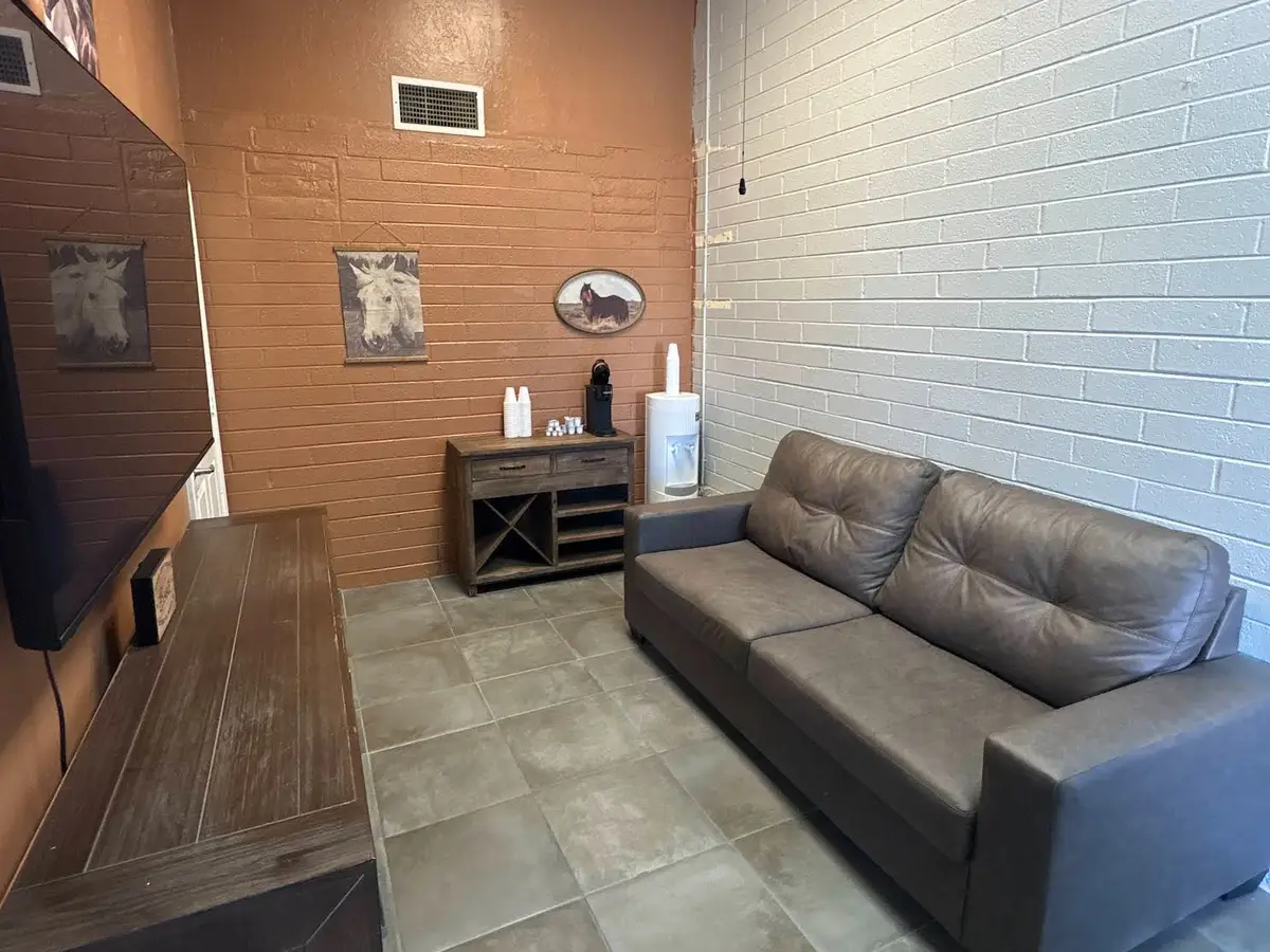 Waiting room with a leather sofa, wood console and tile floor at Monroe Automotive